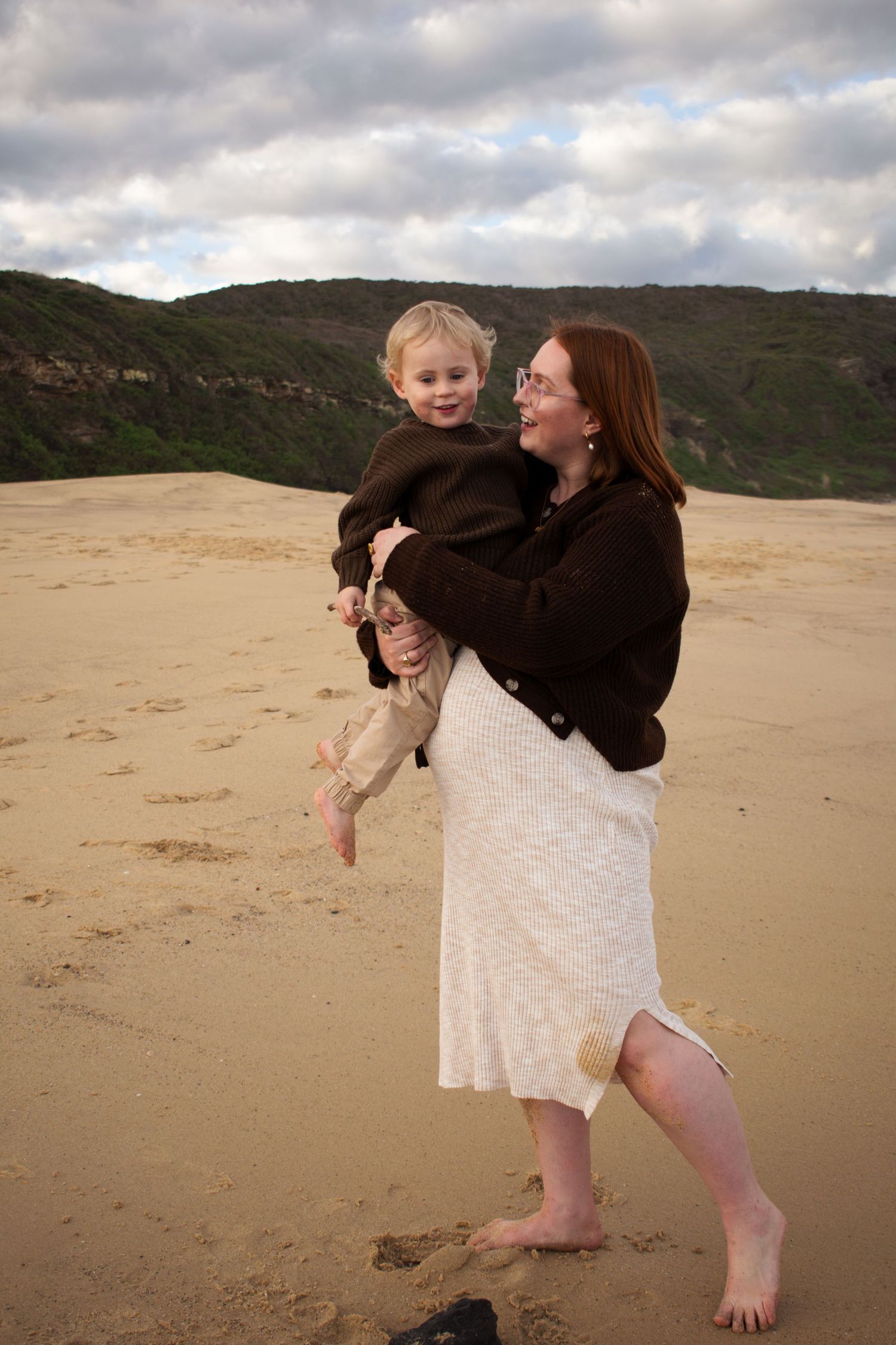 Newcastle maternity photographer capturing mother-to-be at beach with toddler