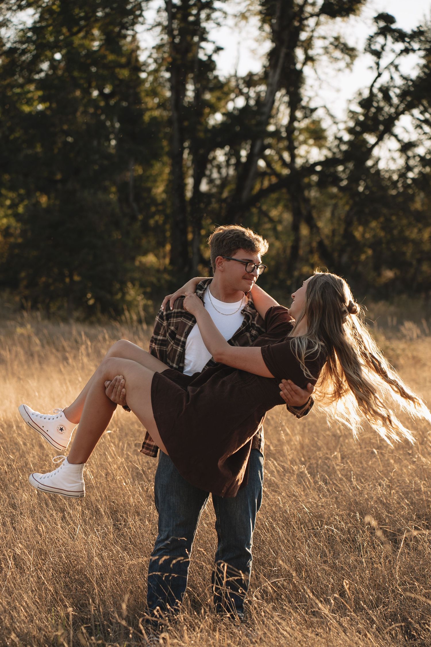 Playful engagement photos of a couple dancing and dipping in a golden sunlit field.