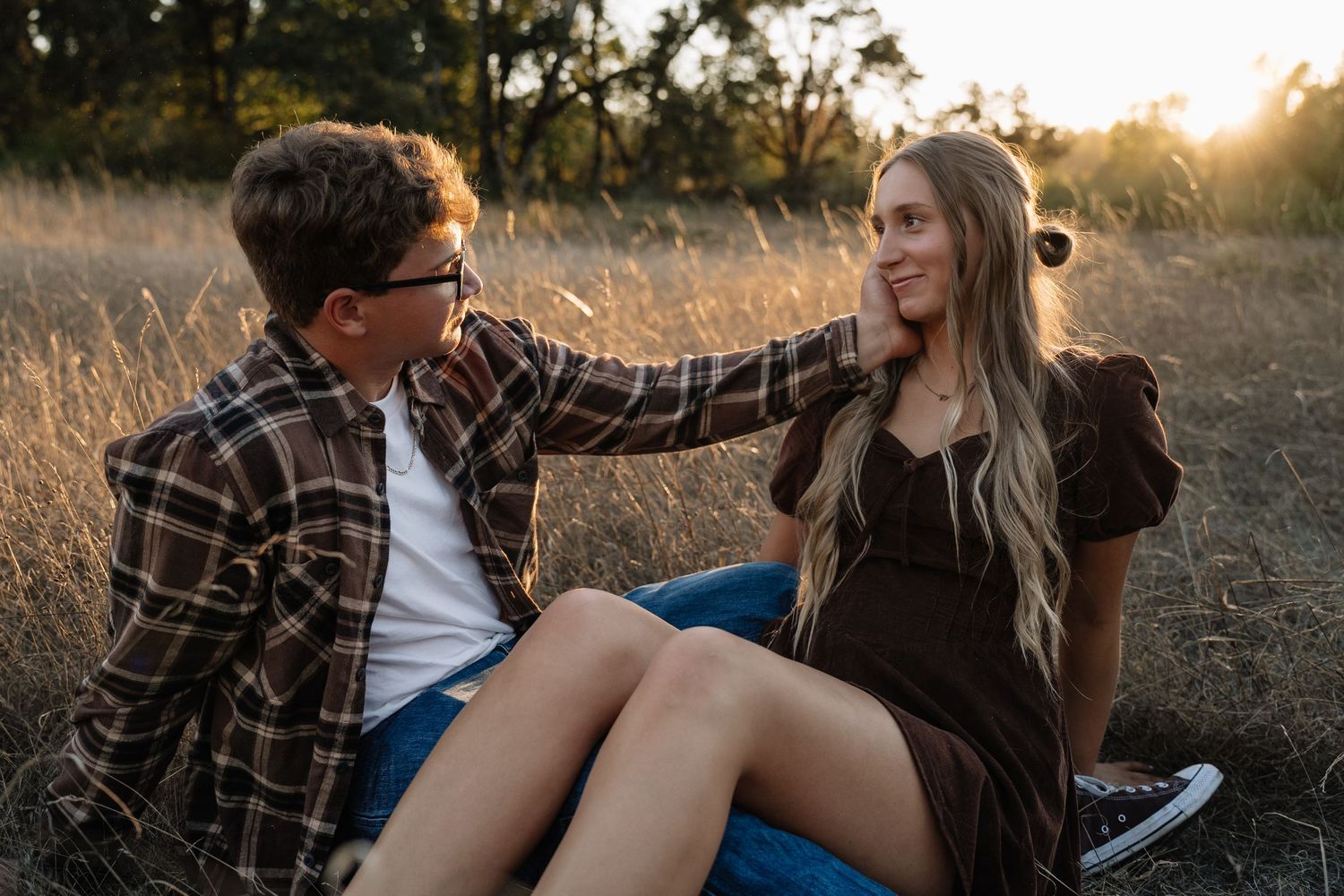 A romantic sunset engagement session showing a couple laughing together in a field.