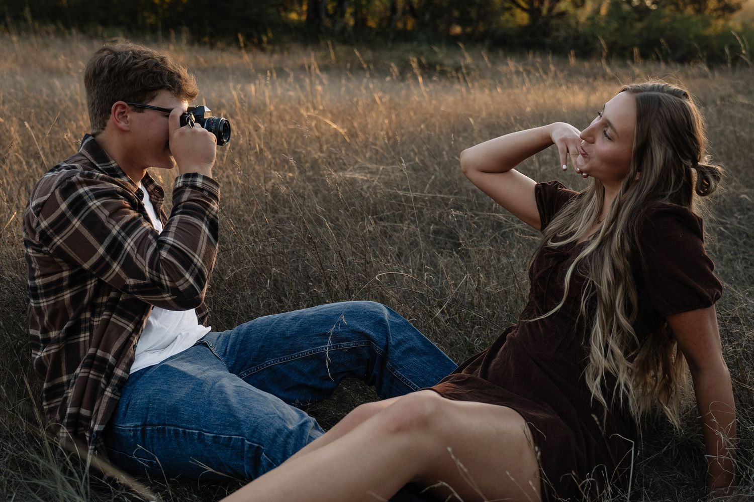 An intimate engagement photo series showing a couple laying in a grassy field at sunset.