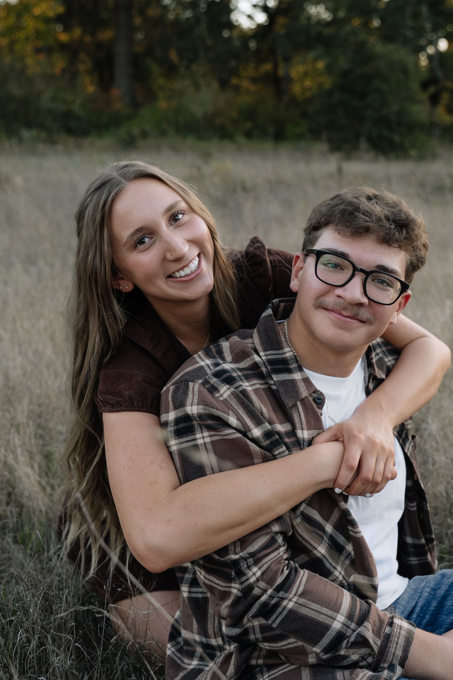 A playful engagement photo sequence showing a couple laughing and embracing in tall grass.