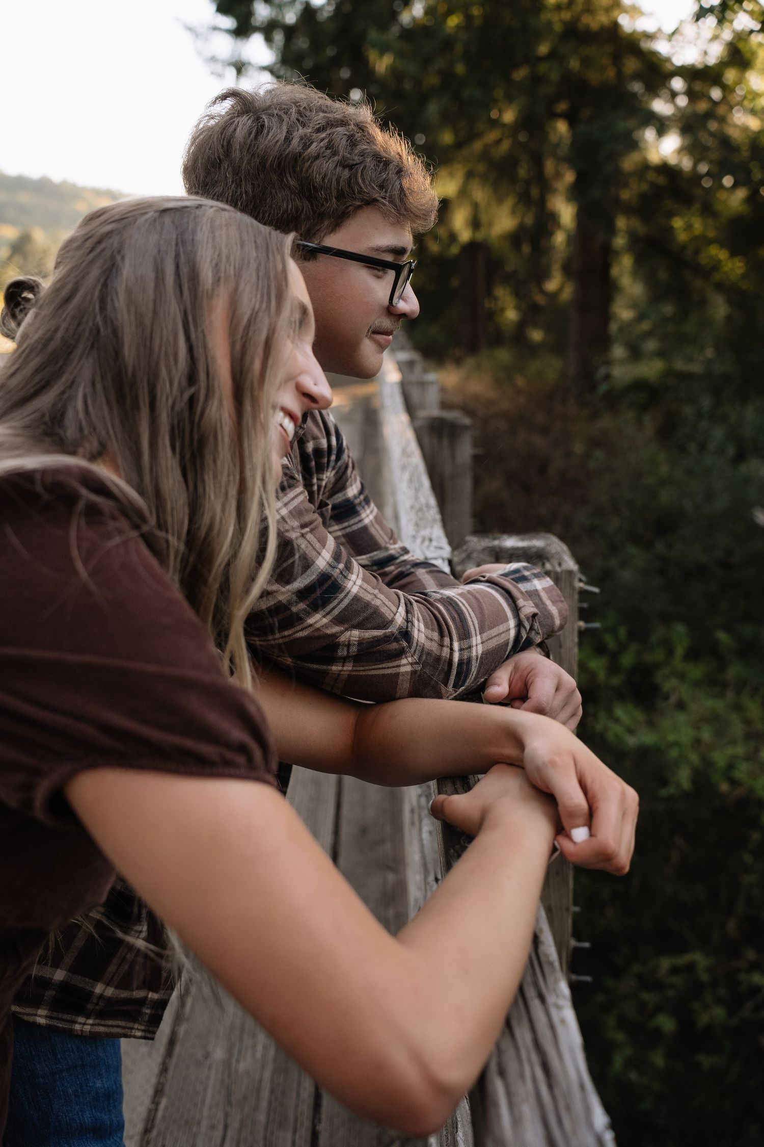 A couple sits close together during an outdoor autumn engagement photo session.