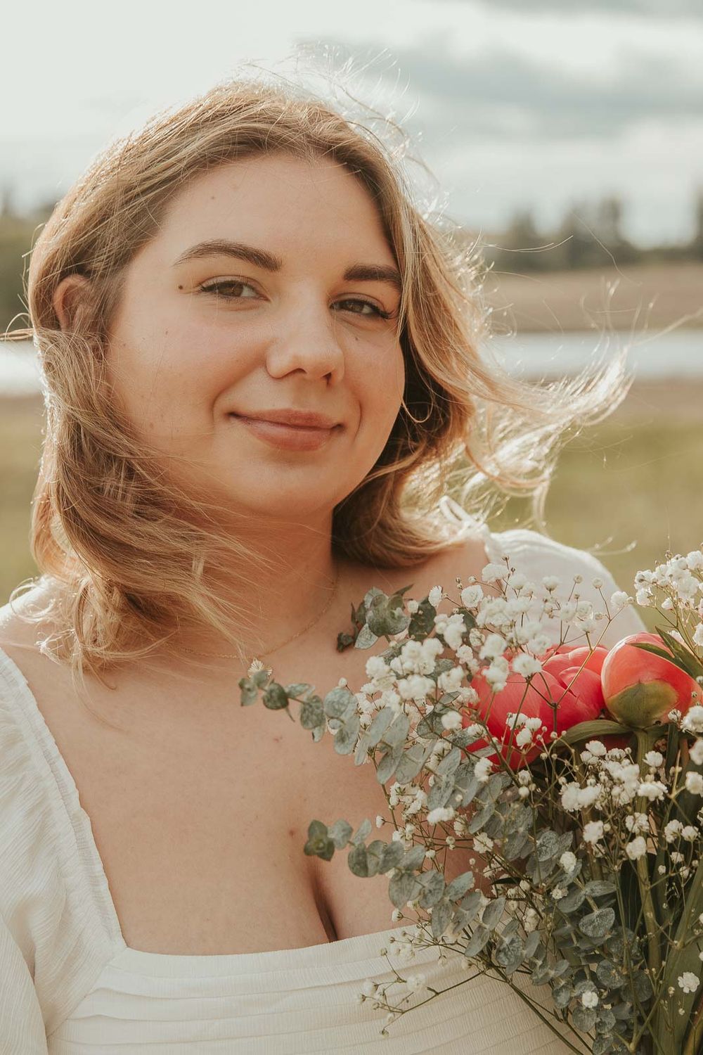 Close-up of smiling senior from Davenport High School holding trader joes flowers during golden hour senior session in field near Spokane