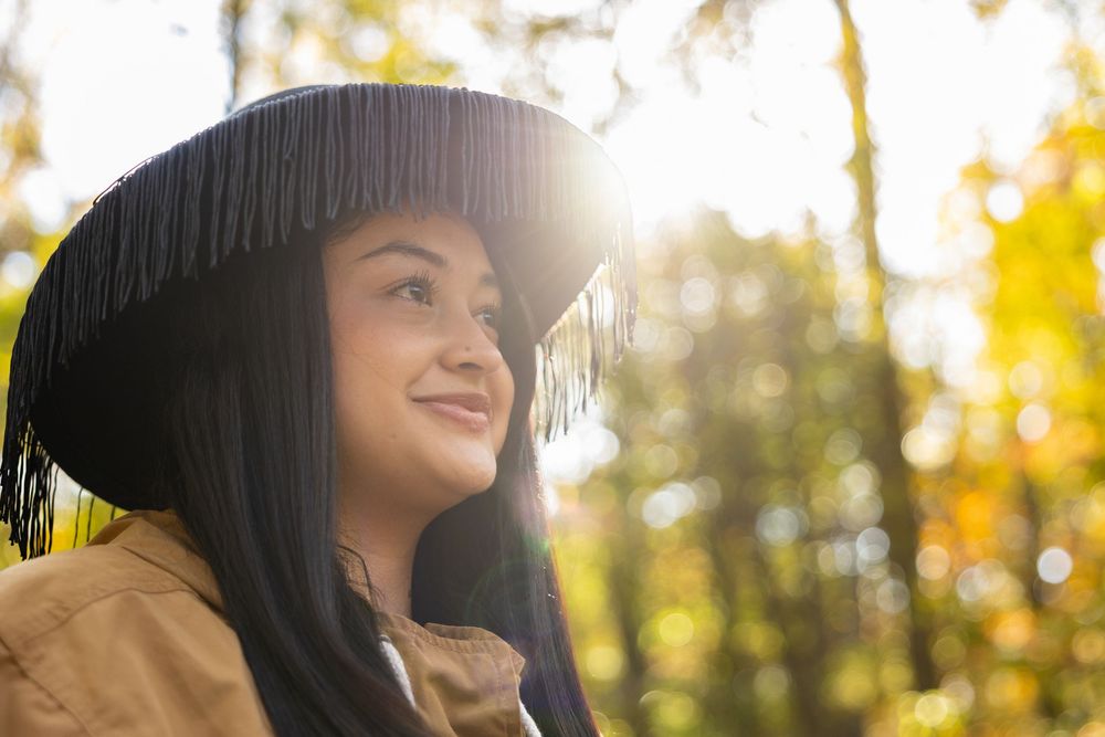 Lifestyle portrait of woman in wide-brim hat glowing in fall sunlight — candid outdoor photography