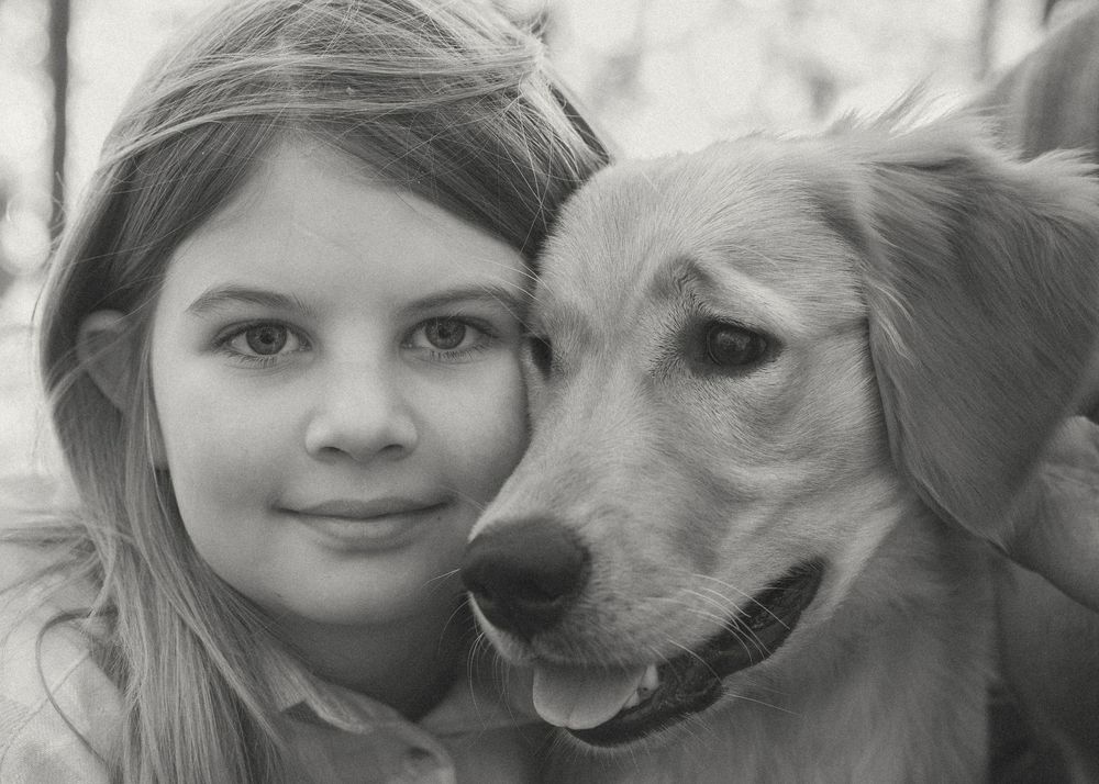 Black and white portrait of young girl cuddling her dog — natural light family photography
