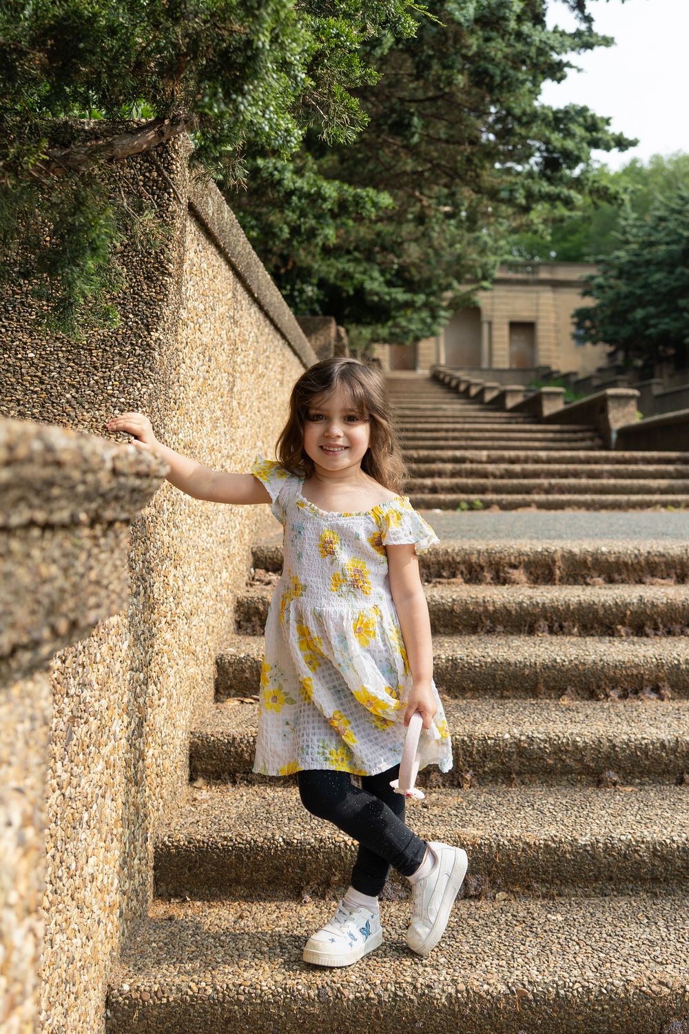 Little girl smiling on stone staircase outdoors — playful child lifestyle photography