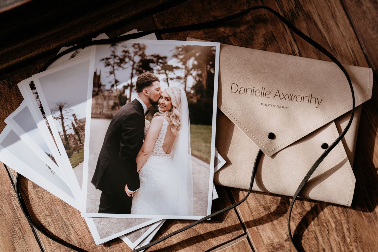 Wedding photos and an envelope labeled 'Do it for the dance' displayed on a rustic wooden surface in natural light.