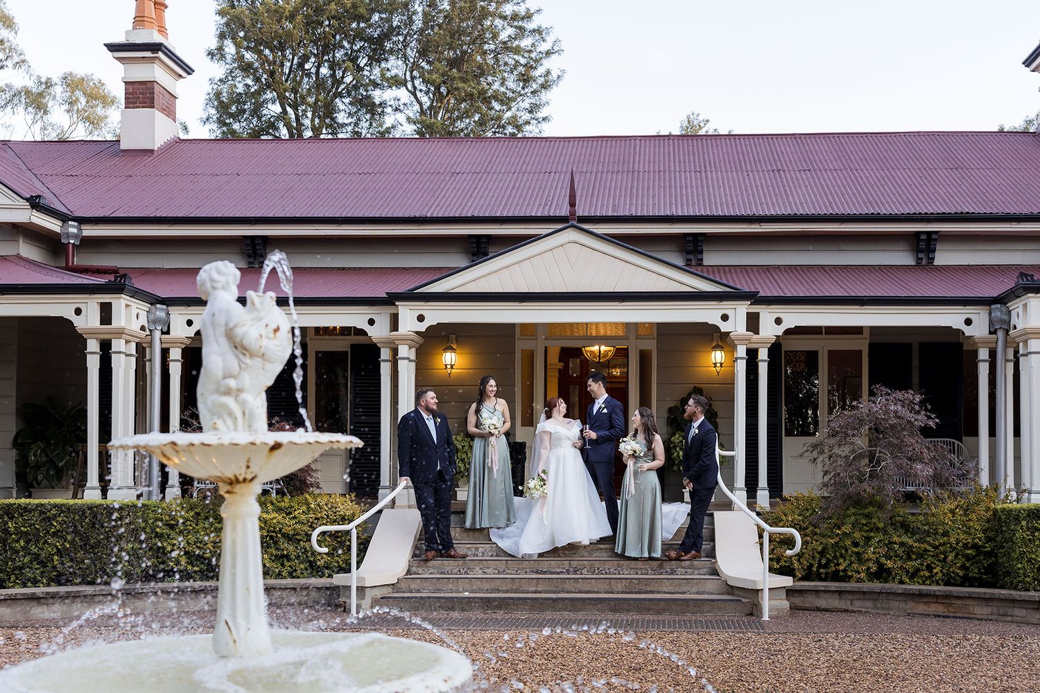 Traditional wedding ceremony participants gather on a brick-paved walkway in front of a columned Southern-style porch entrance at Gabbinbar.