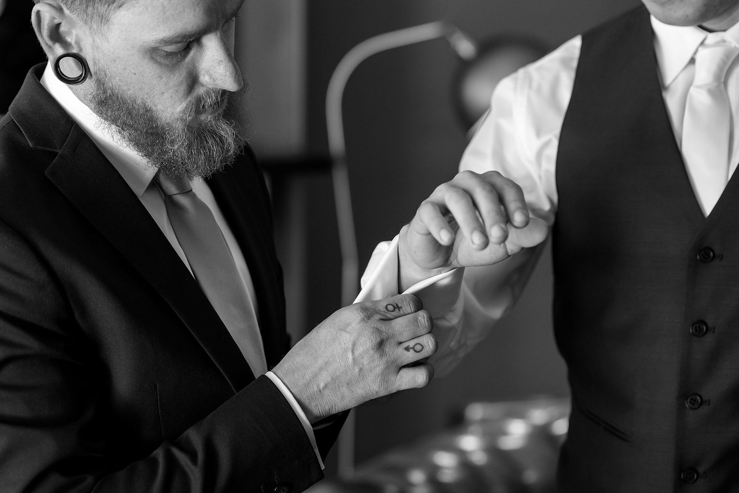 Black and white close-up of a Groomsman helping the Groom with his cuff links in the Library at Gabbinbar Homestead Toowoomba.