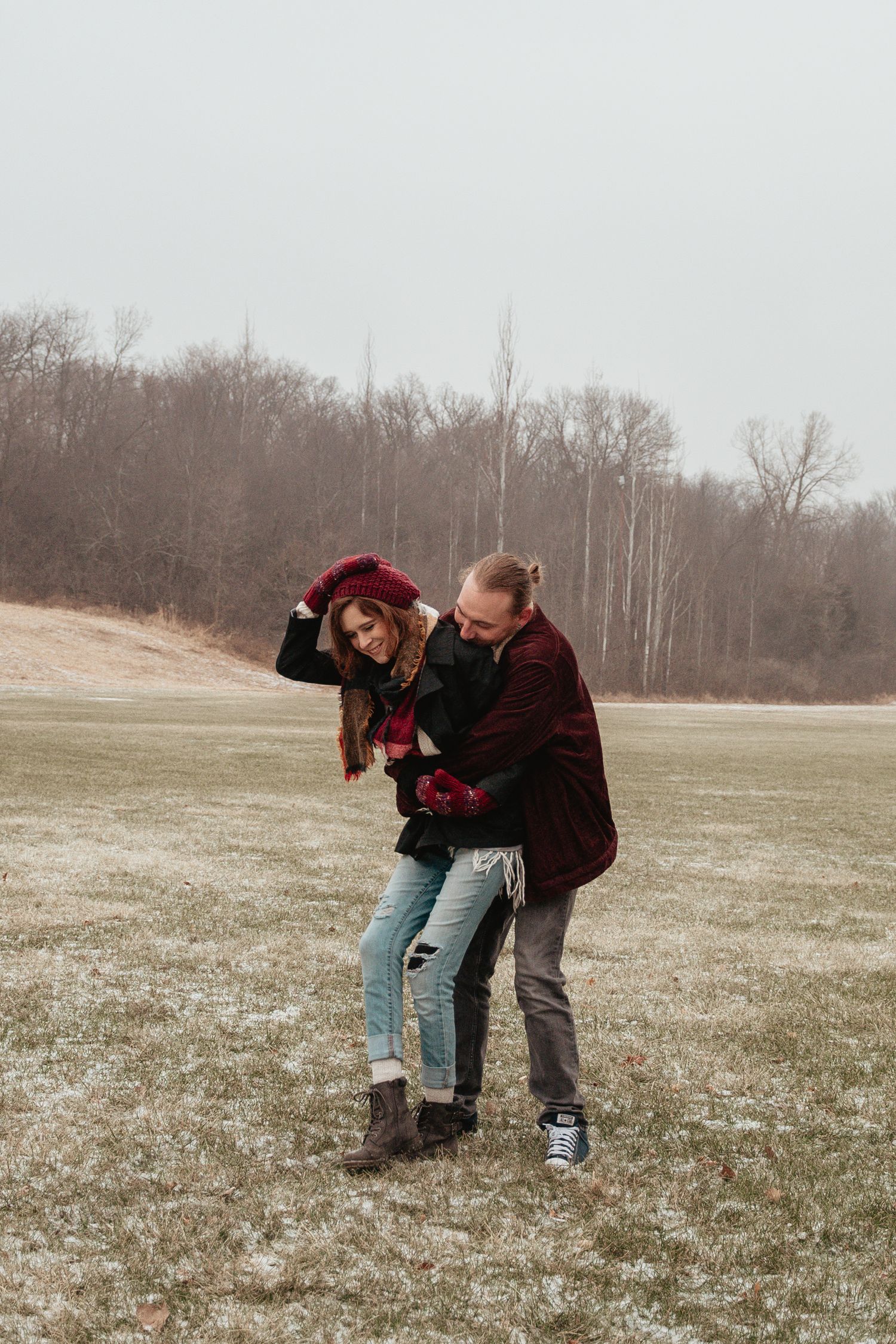 Playful winter scene in an open field with burgundy and black outfits.