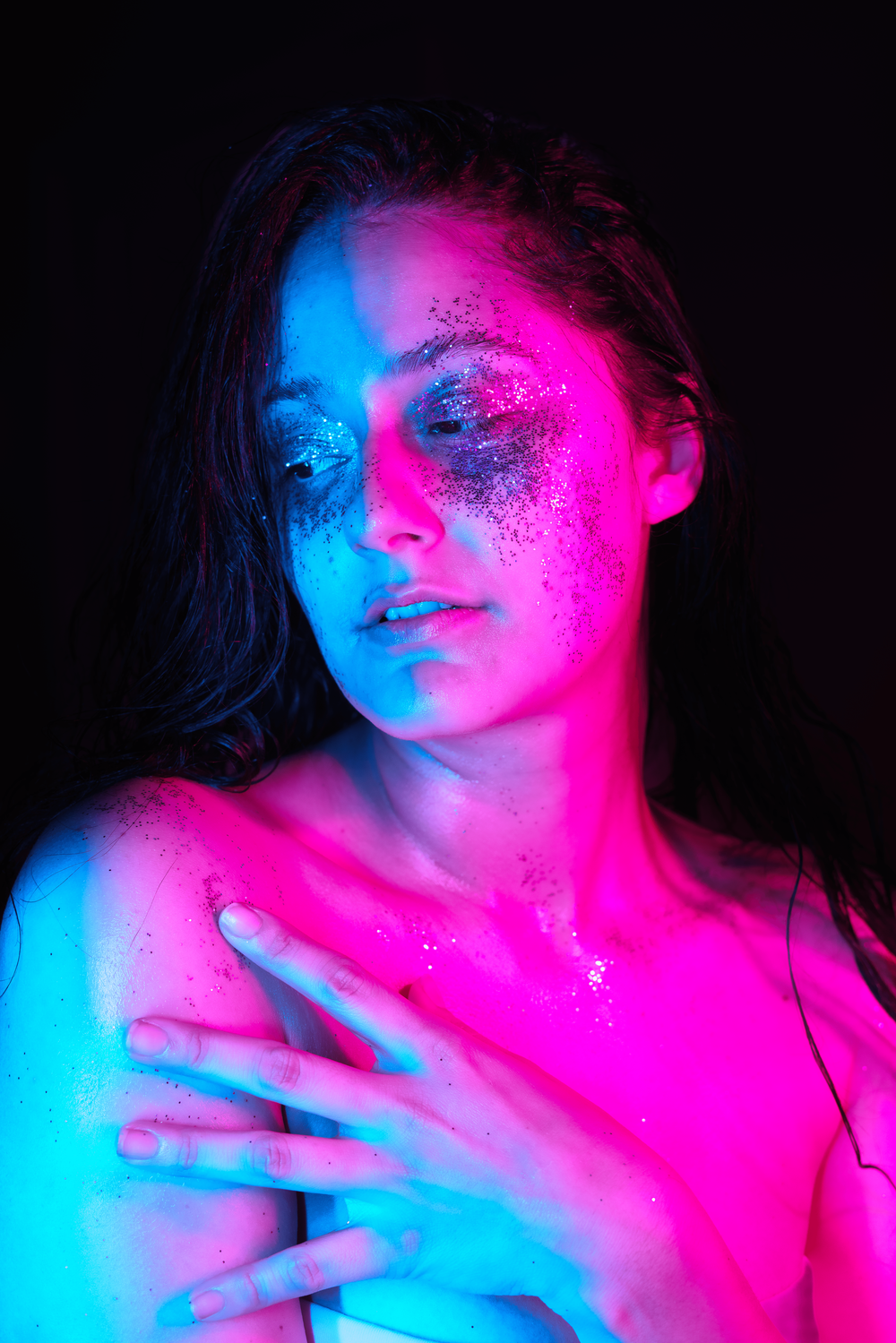 Vidalia Modeling with glittering eyes, looking over her shoulder back to the camera while bathed in euphoric pink and blue light