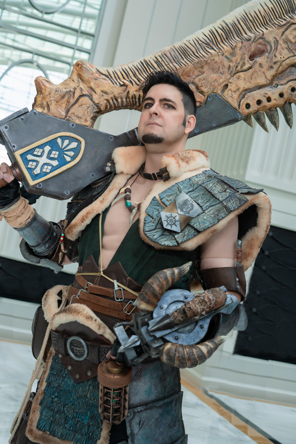 Commiownist Cosplay in a stoic pose as the Field Team Leader from Monster Hunter World, set against the Katsucon Halls