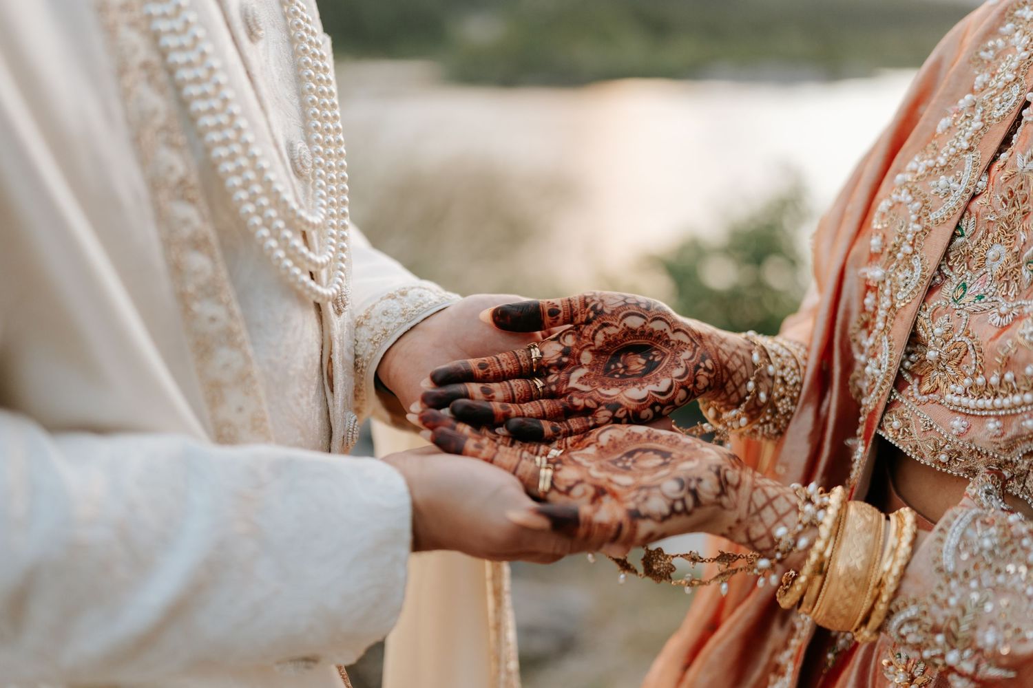 Close-up of hands showing traditional henna designs at a wedding ceremony.