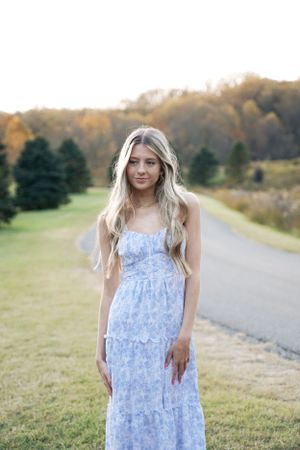 Outdoor portrait in a blue floral dress on a scenic country path.