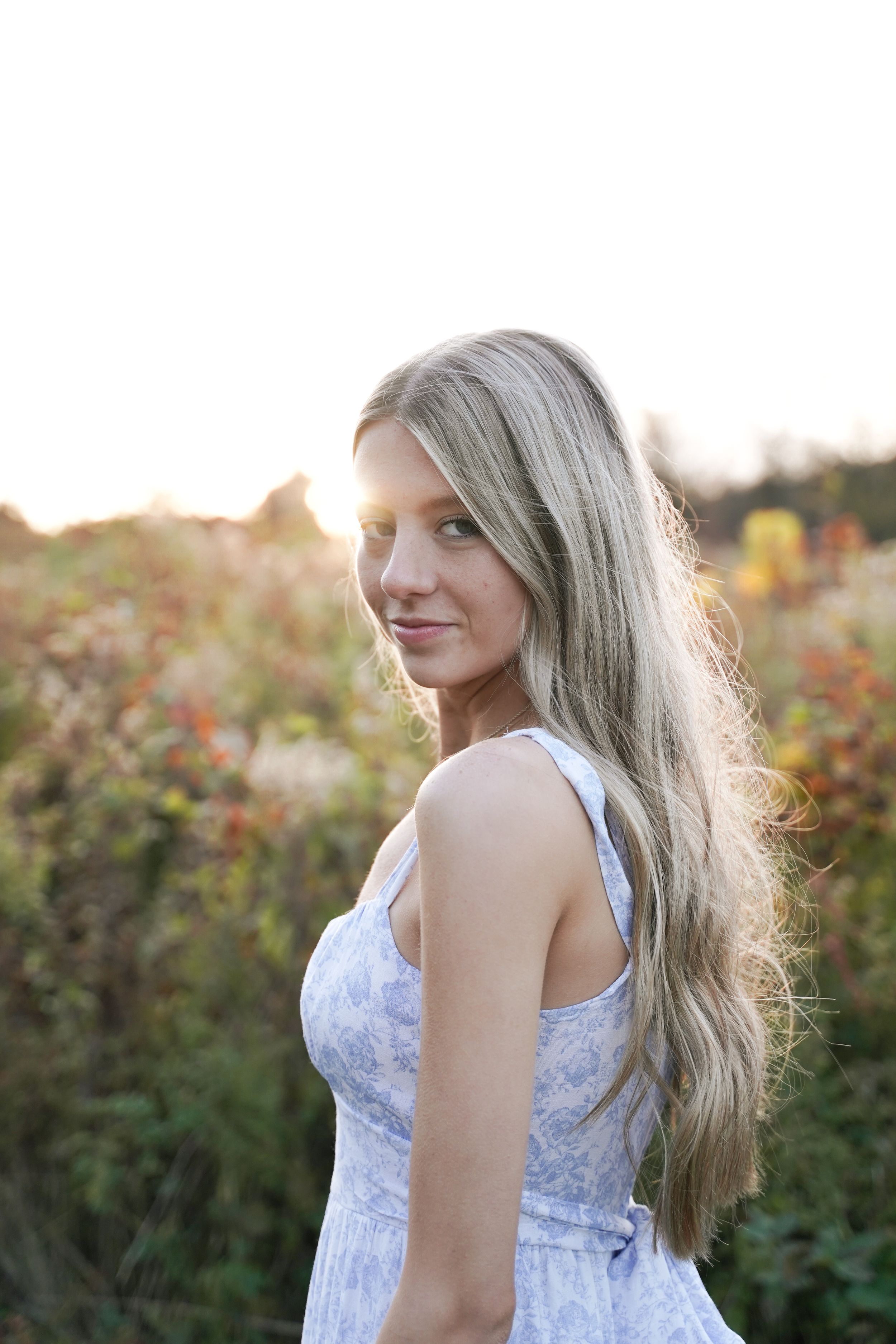 Portrait of a person in a white lace dress with long flowing hair in warm sunset lighting.