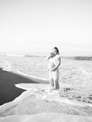A romantic couple embraces on a scenic beach at sunset in black and white photography.