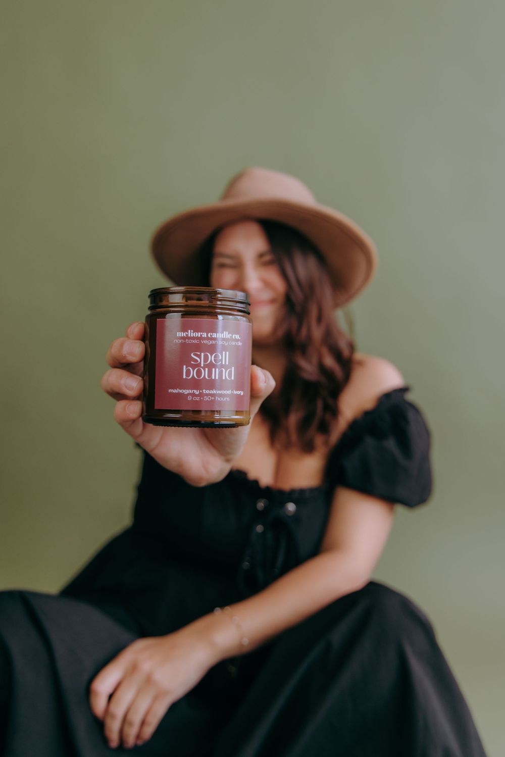 Artistic product photography featuring a jar of skincare cream held by someone wearing a black off-shoulder dress.