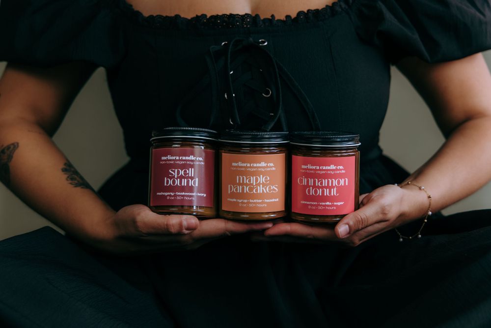 Multiple skincare product jars displayed on a dark surface with hands holding them.