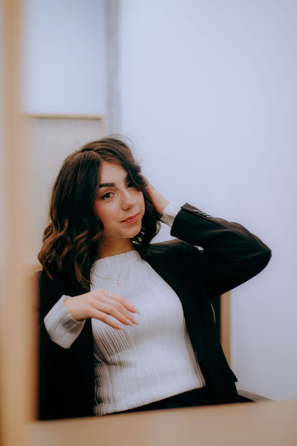 A series of artistic portraits showing relaxed poses in a white sweater and black blazer against a light background.