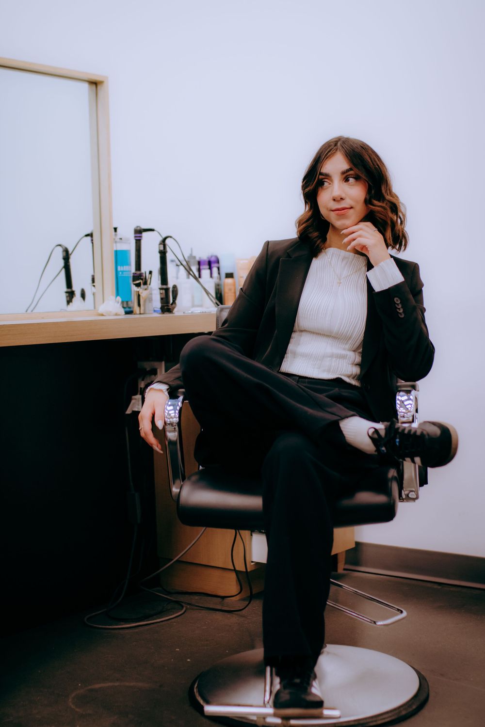Candid fashion portraits taken in a salon chair showing casual poses in business attire.