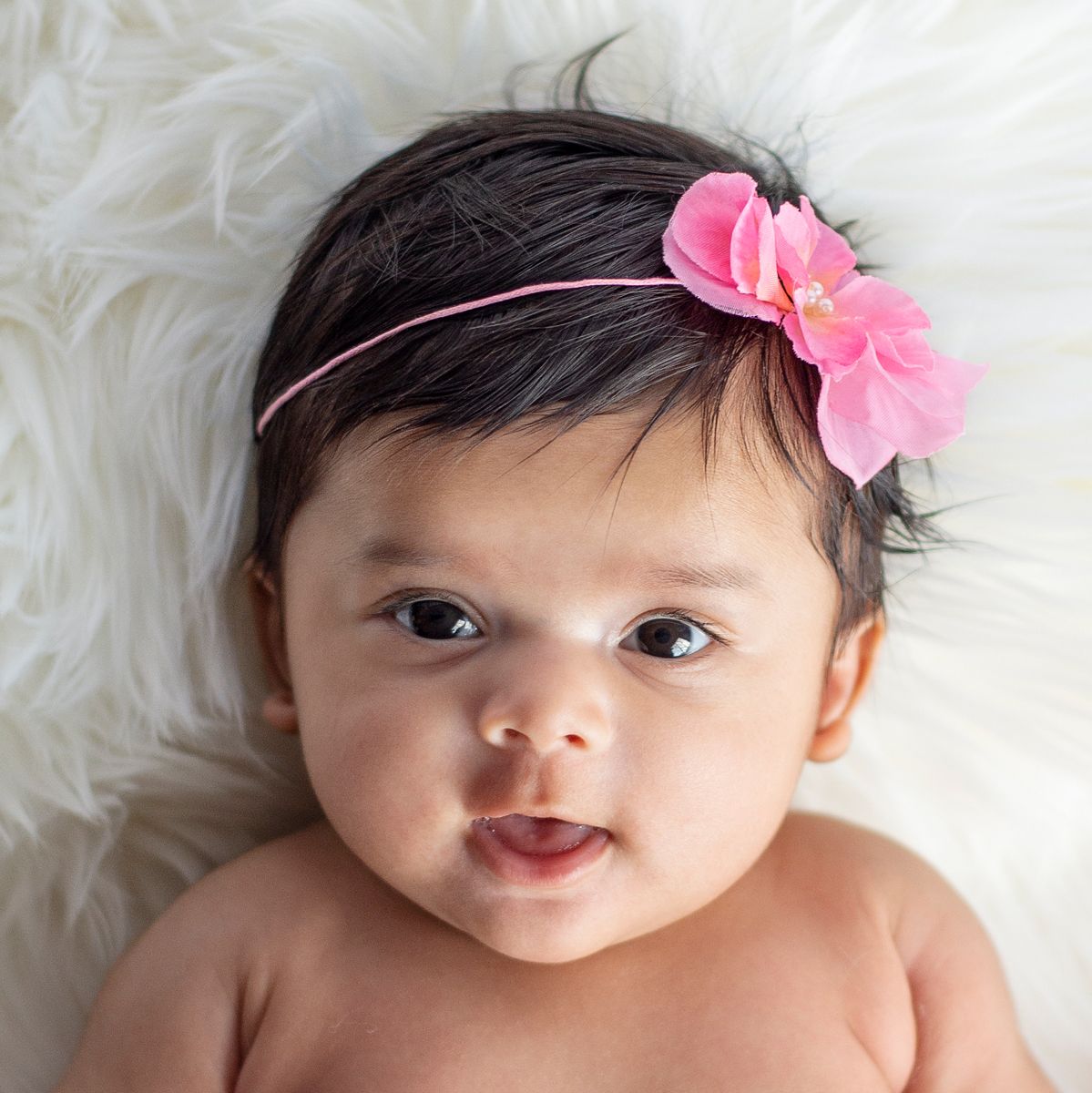 close up of face of 4 month old girl smiling with pink floral headband