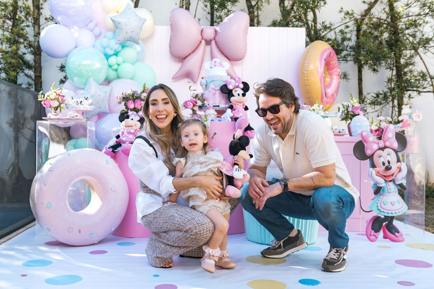 Colorful birthday party setting with balloons, white picket fence, and superhero decorations arranged on a blue table.