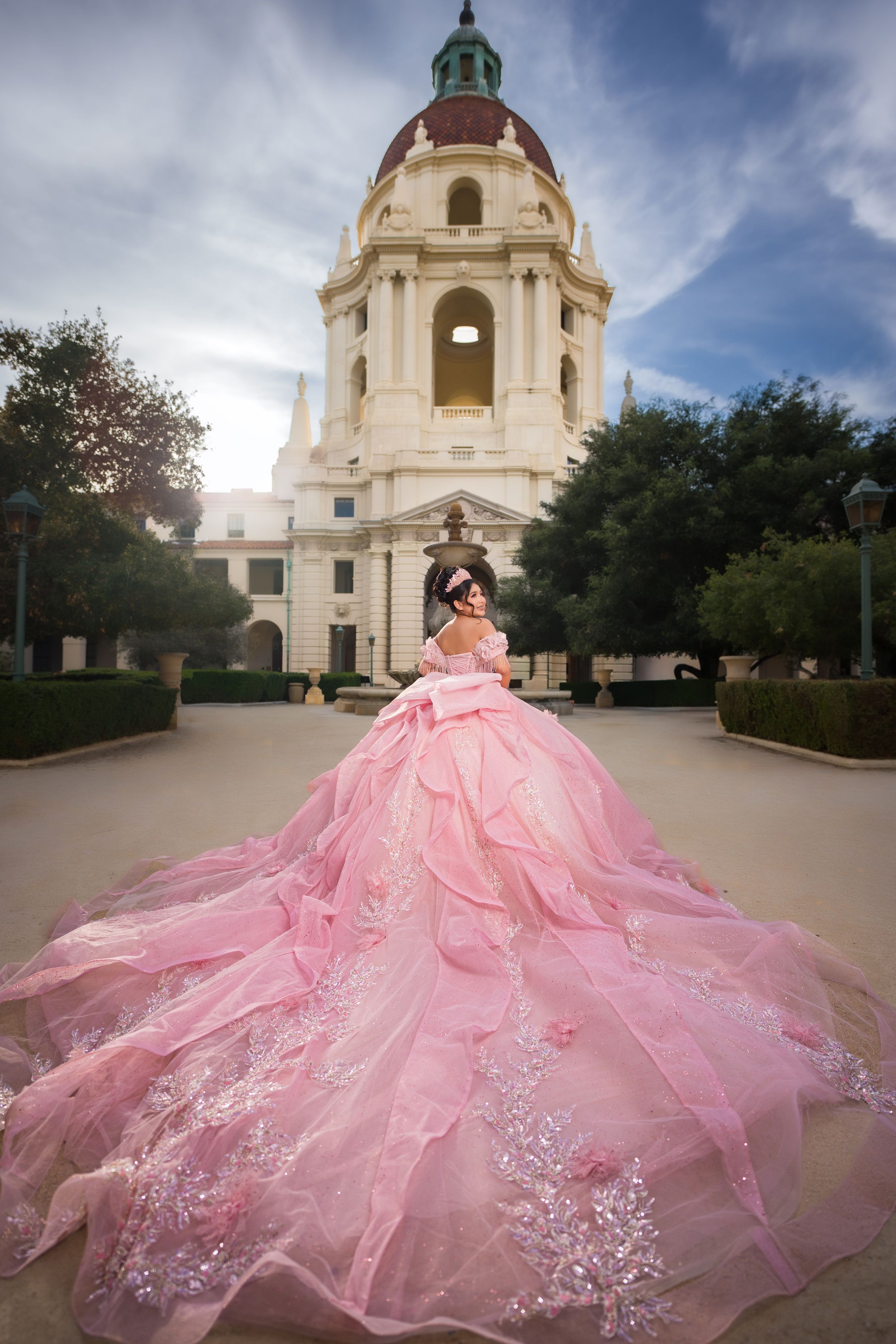 A pink quinceañera dress with a flowing tulle skirt photographed in front of the Pasadena City Hall dome.