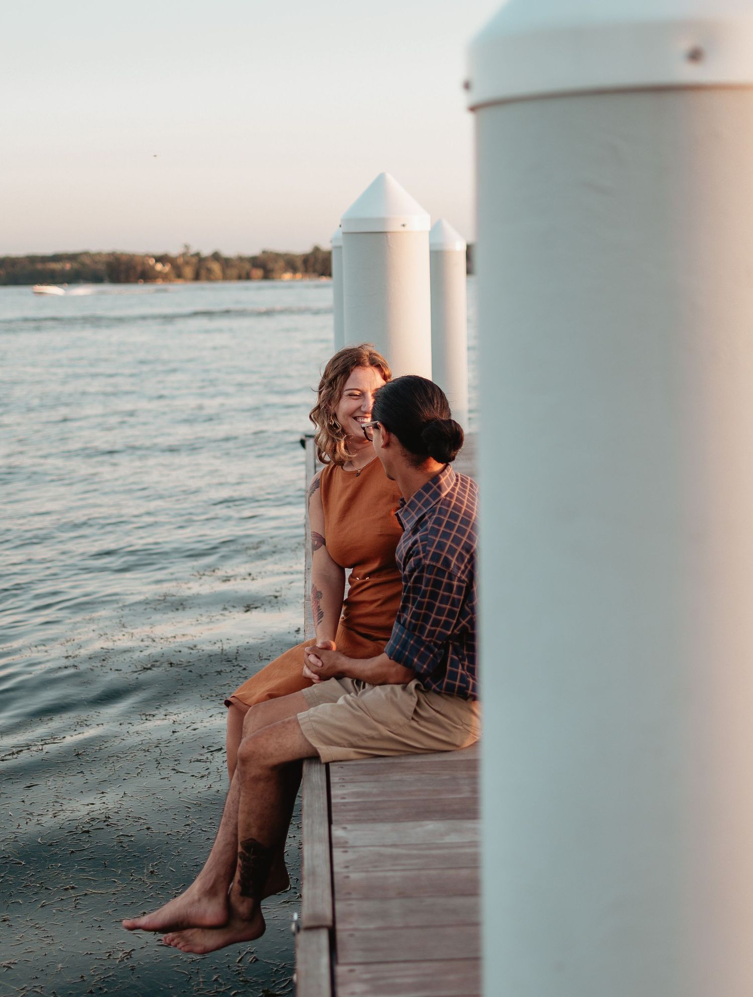 A couple shares an intimate moment at sunset while sitting on a wooden dock by the water.