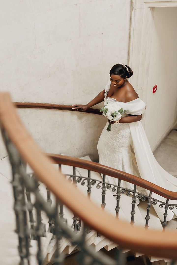 A romantic wedding moment captured beneath white floral decor with elegant white attire.