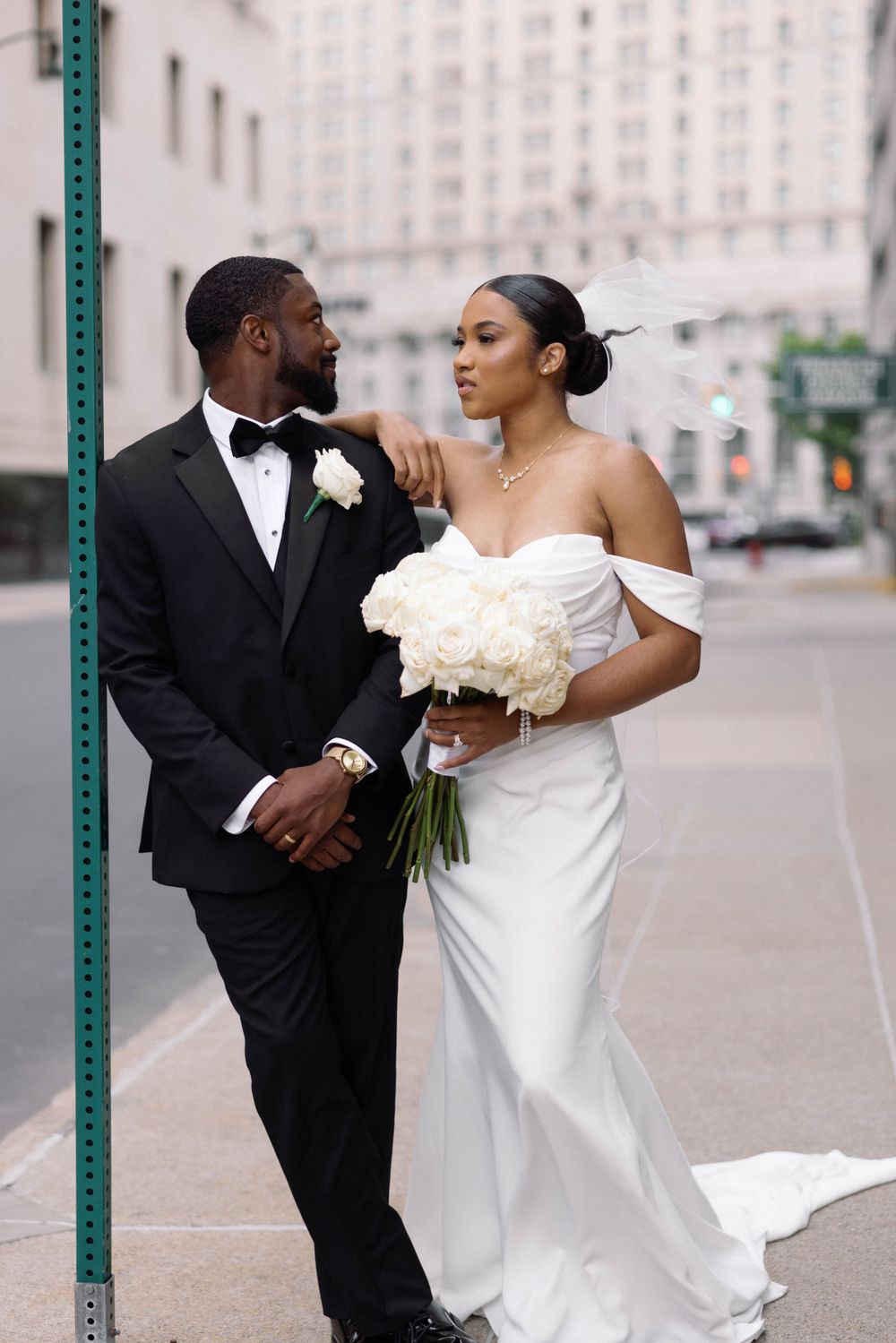 Bride and groom share intimate moment on city street during wedding photoshoot.