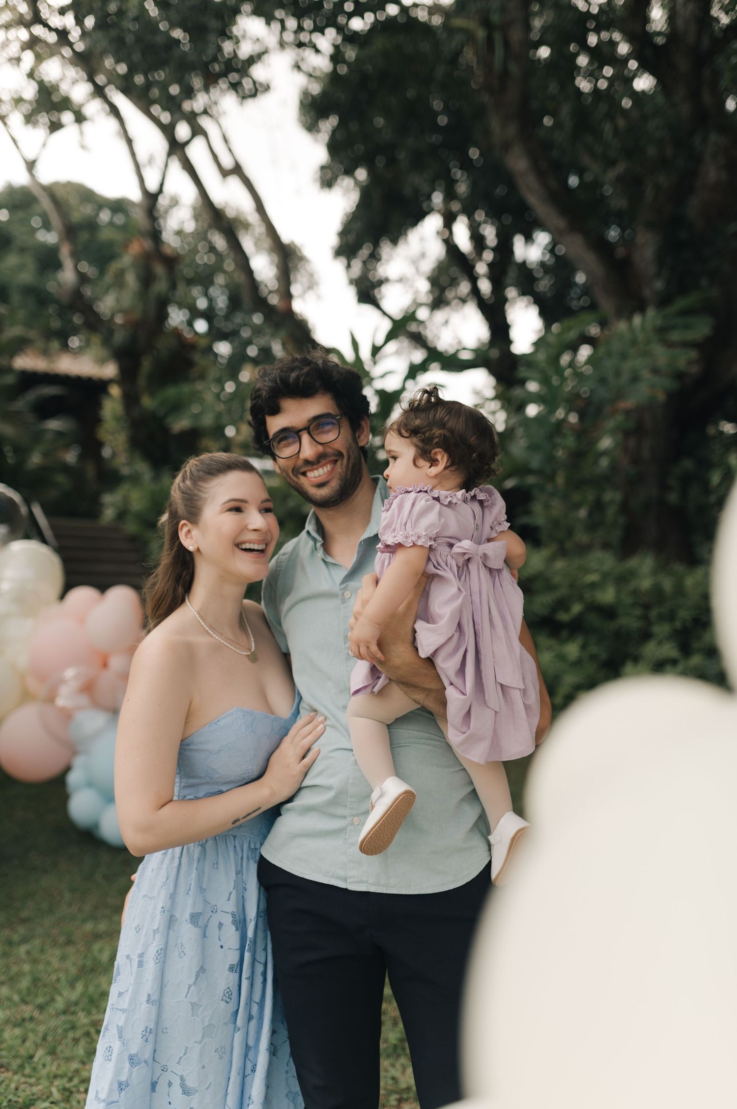 Family celebration in garden setting with pastel balloon decorations.