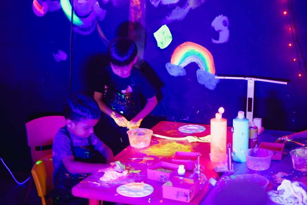 People gathered around table with glowing decorations and neon lighting effects.
