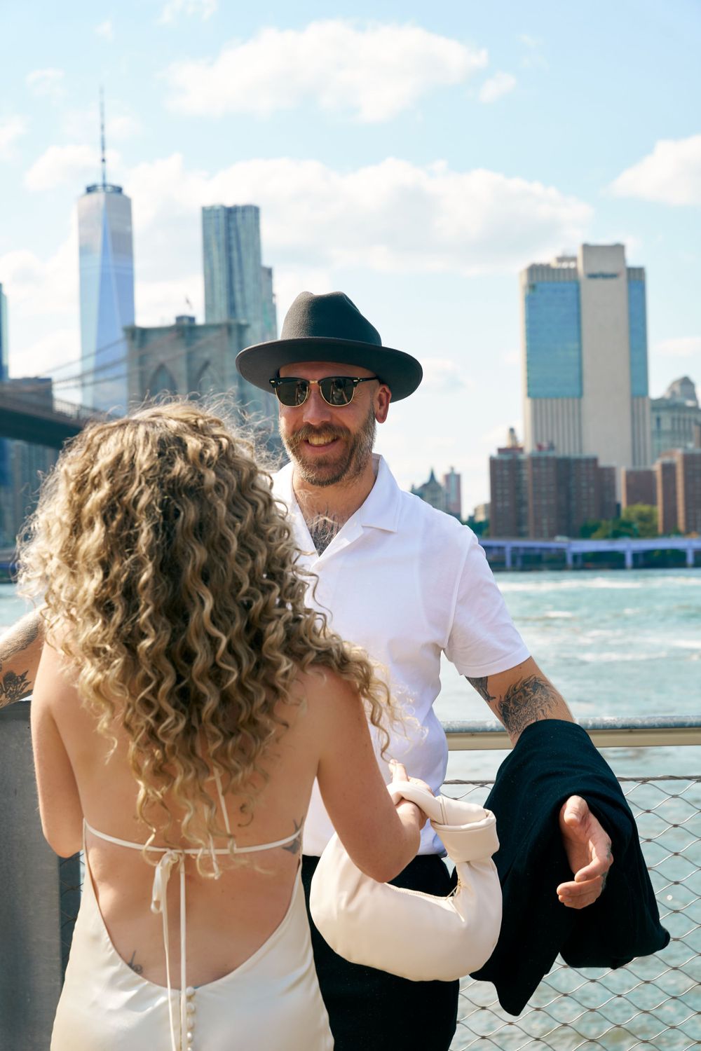 Couple on waterfront with Manhattan skyline and One World Trade Center in background.