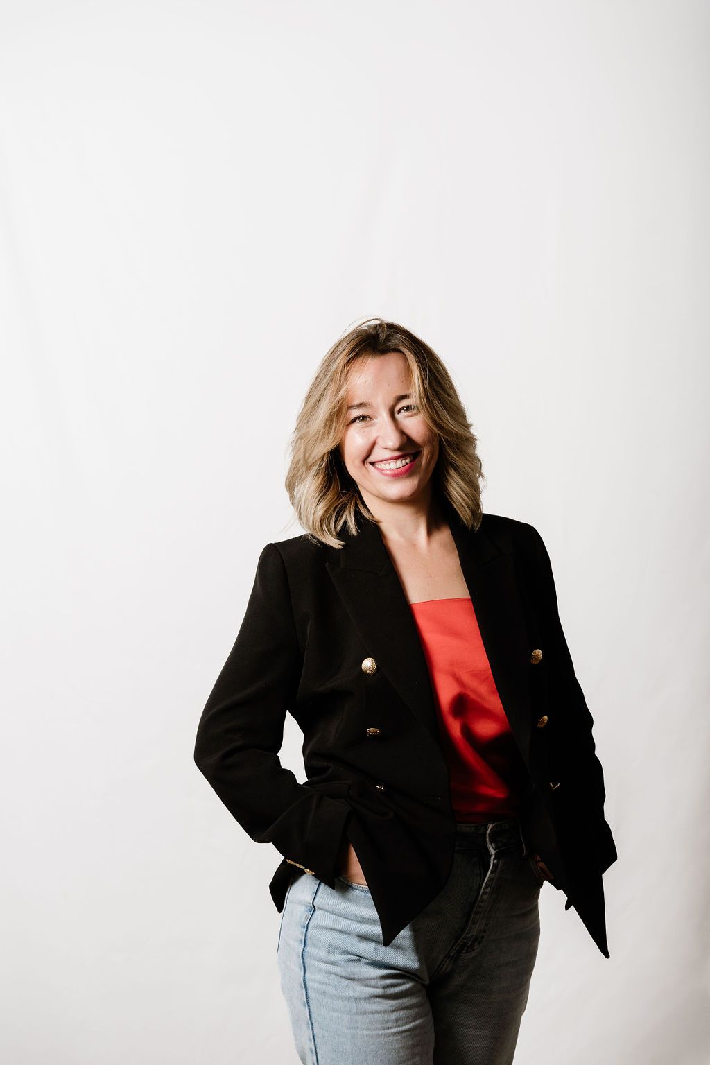 Studio portrait session against white backdrop featuring casual black blazer and denim outfit.