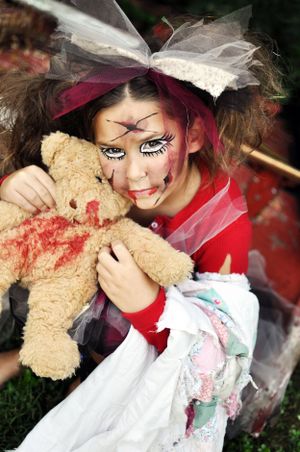 Spooky Halloween costume with face paint and bloody teddy bear prop.