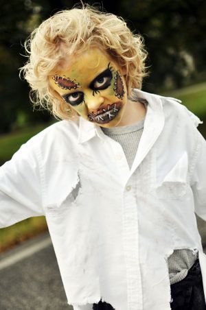 Creative Halloween zombie makeup with curly blonde hair and white button-down shirt for spooky costume effect.