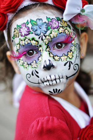 Colorful Day of the Dead sugar skull face paint design with floral patterns and colorful decorative elements on a white base.