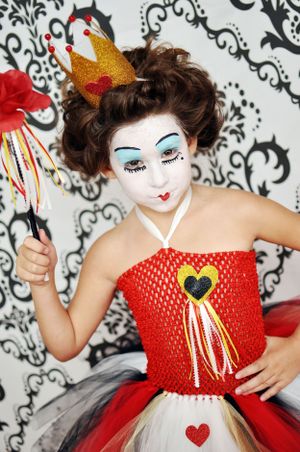 Whimsical Queen of Hearts costume with white face paint, crown and red tulle dress.