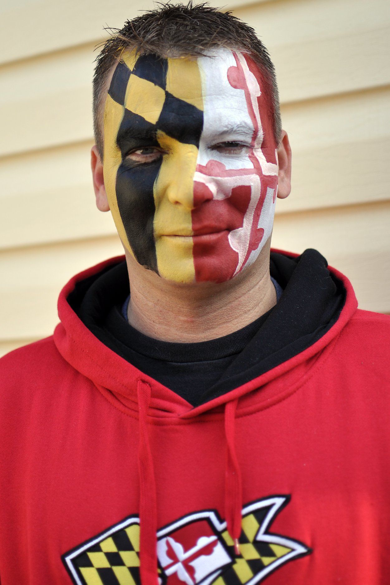 Maryland state flag colors painted on face with black hoodie showing state pride and team spirit.