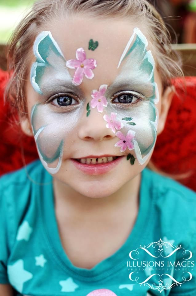 Child with blue and white butterfly face paint design with pink flowers.