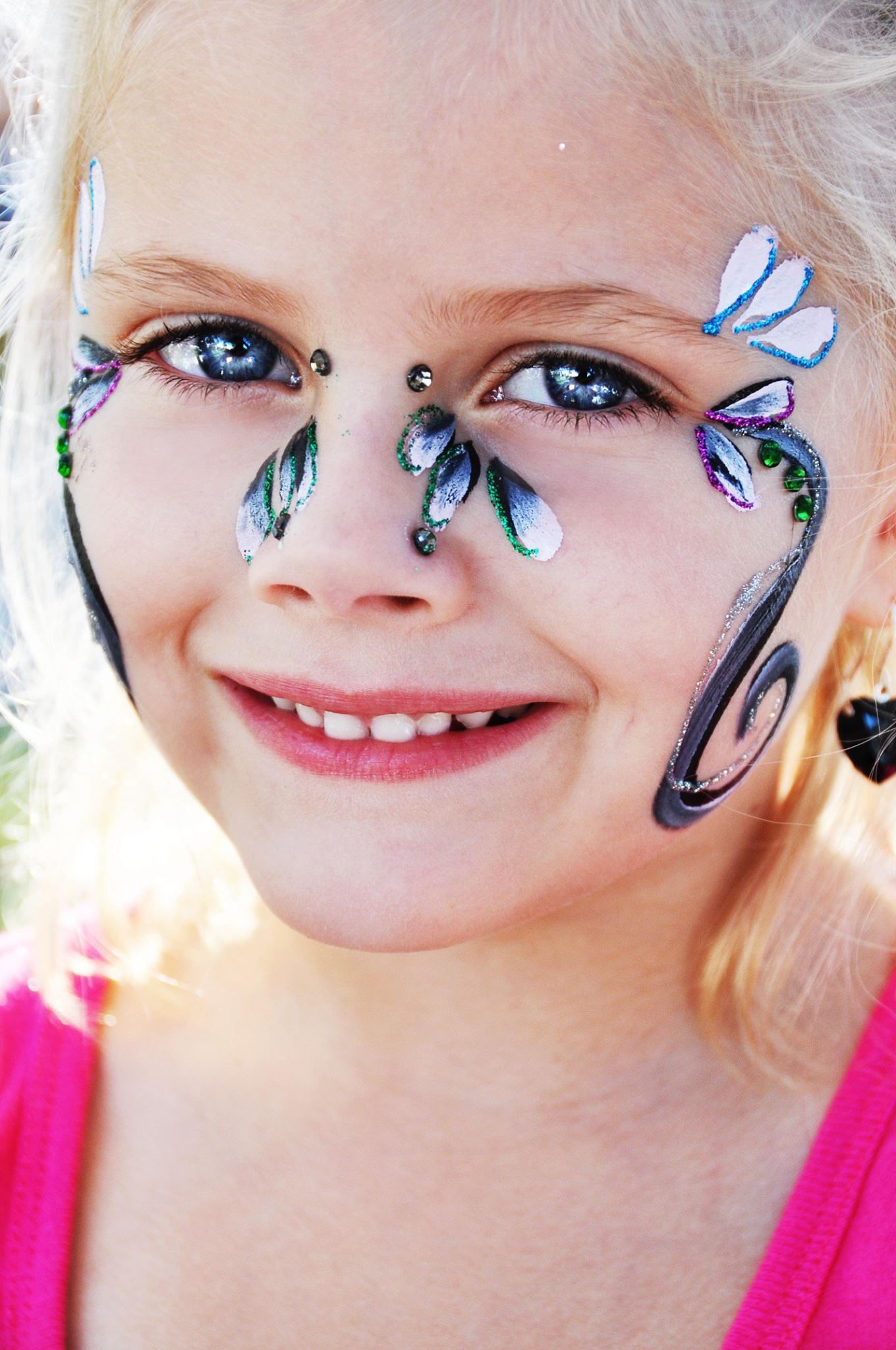 Delicate blue butterfly face paint design with sparkles around the eyes.