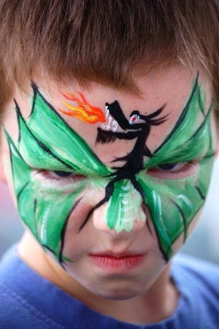 Dragon face paint design featuring green wings and black silhouette with flames.