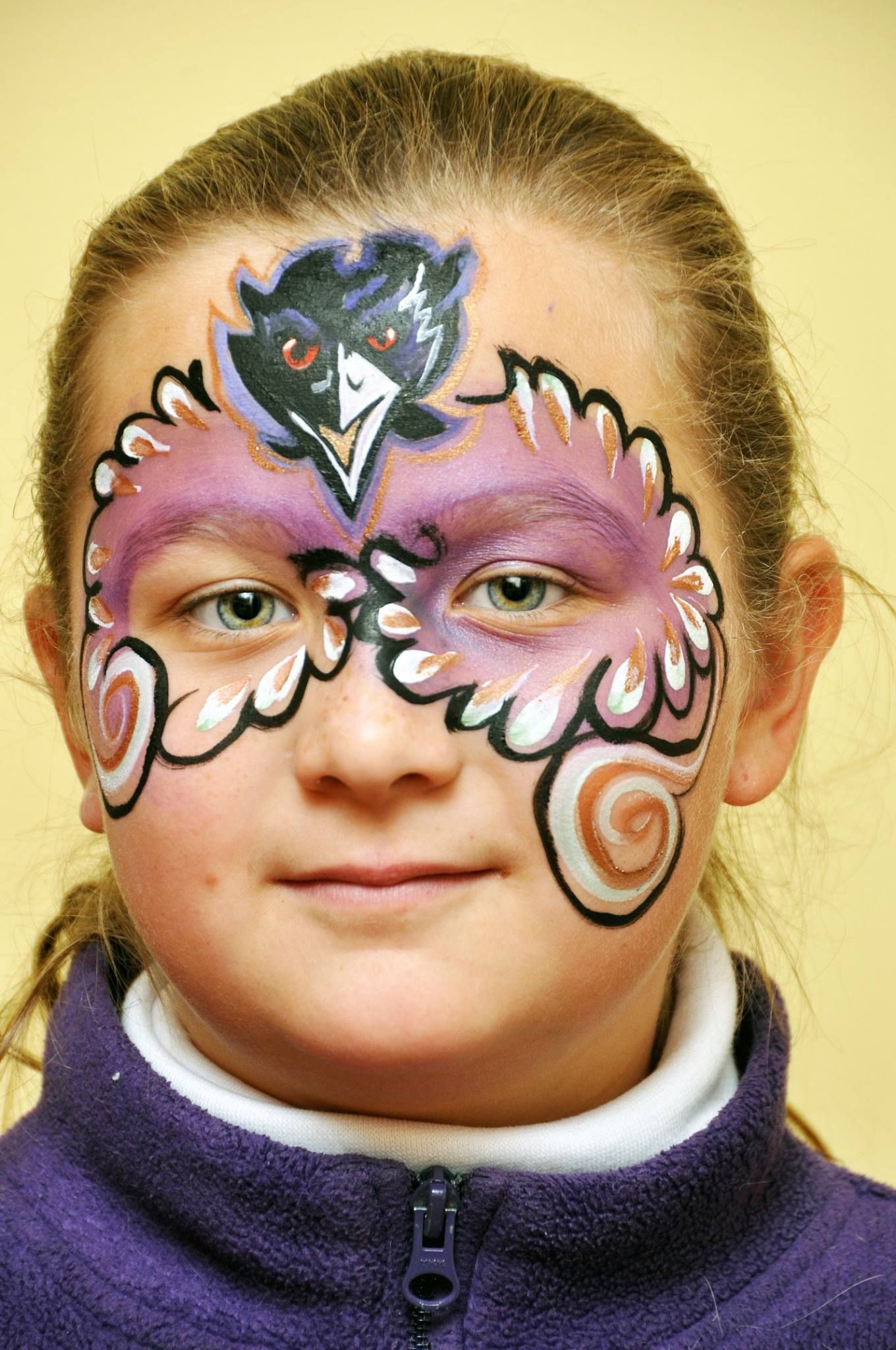 Decorative mask-like face paint design with Raven Football.