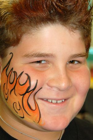 Orange flame face paint design decorates one cheek.