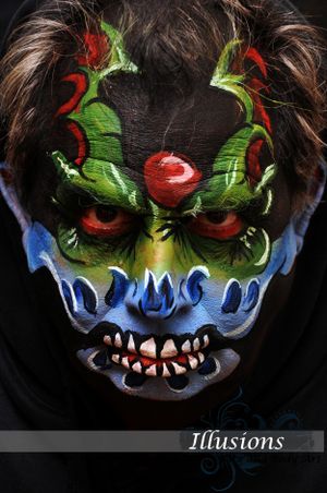 Monster face paint with green and red details creating scary demonic effect.