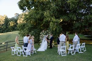 White folding chairs set up on a grassy lawn for an outdoor wedding ceremony.