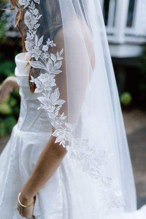 Close-up detail of delicate lace floral embroidery on a white wedding veil.