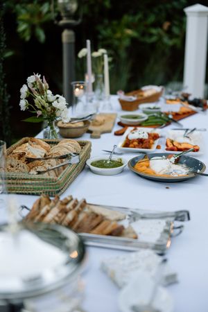 Elegant wedding reception table spread with bread, appetizers and place settings on white tablecloth.