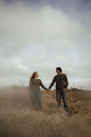 Two people share an intimate moment while standing in a field of dried grass.