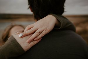 Close-up of hands tenderly embracing against an autumn landscape background.